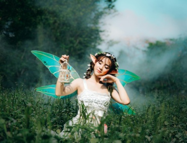 woman in white dress wearing green fairy wings