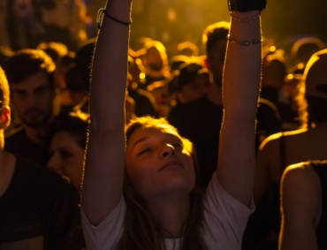 woman at crowd raising her hand while making heart sign