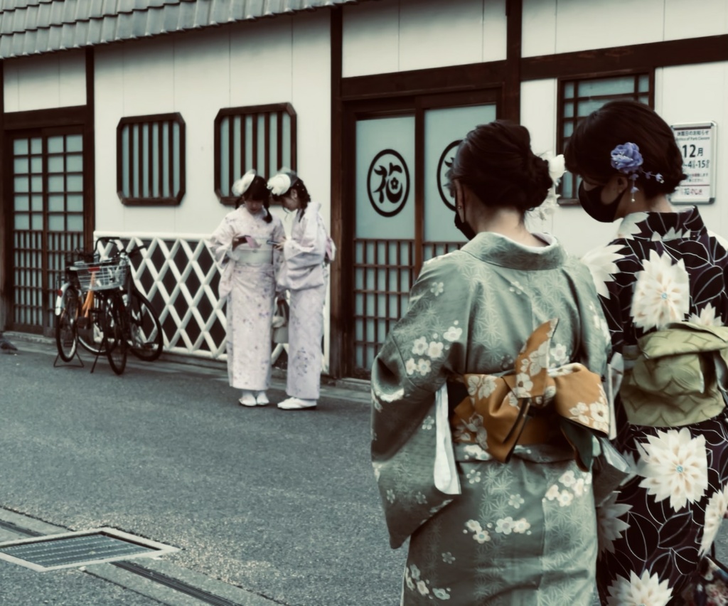 woman in kimono standing on gray asphalt road