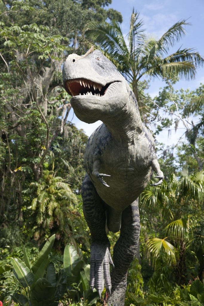 a statue of a dinosaur in the middle of a jungle