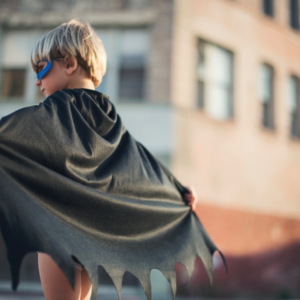 selective focus photography of boy wearing black Batman cape