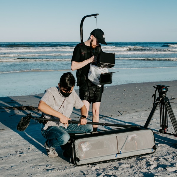 a man is filming another man on the beach
